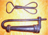 Hänglås av järn, (1700-tal?) Det tångliknade föremålet är låsets nyckel. Med spetsarna klämmer man samman spärrfjädrarna genom de små hål som finns i låshuset. Ett av nyckelhålen skymtar i låsets tjockare del.